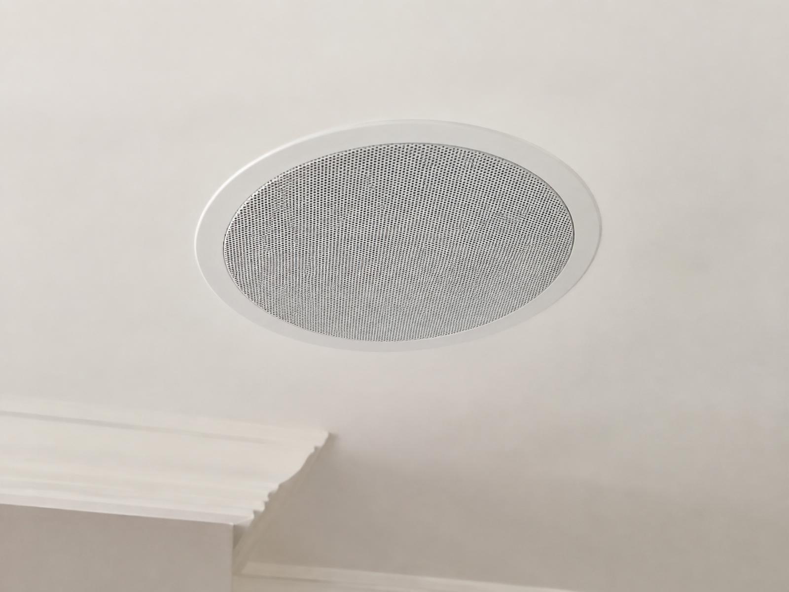 Flush white in-ceiling speaker installed in a smooth plaster ceiling